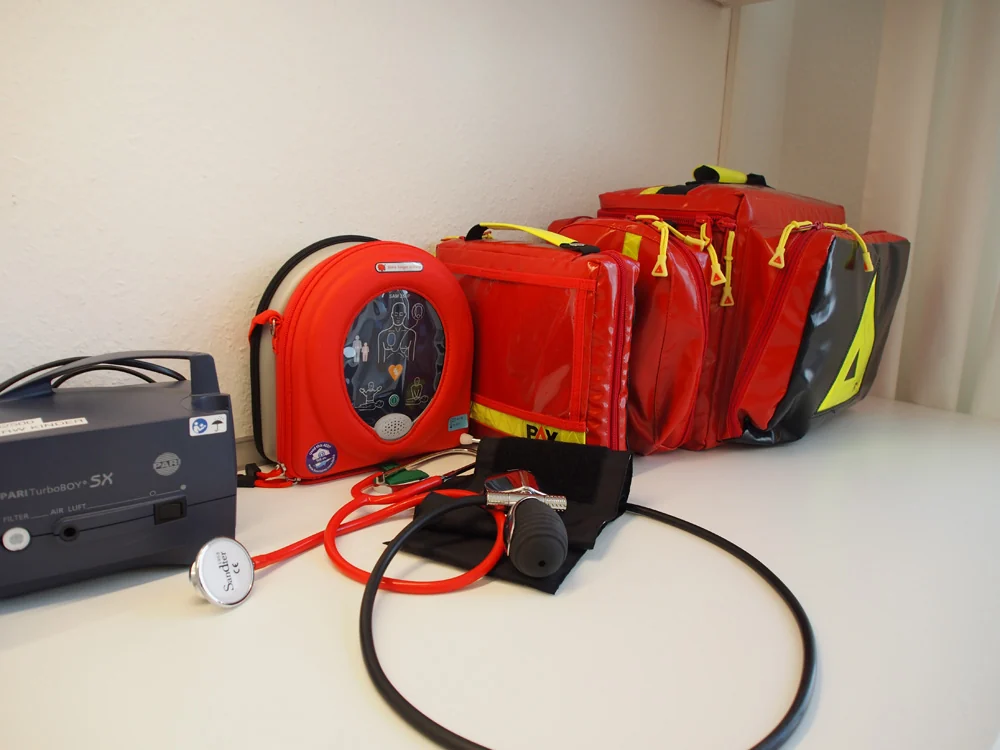 Die rote Notfallausrüstung der Praxis mit Defibrillator und Notfalltaschen