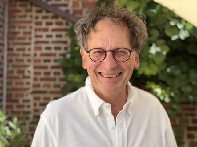 Dr. med. Heiner Klingler vor der begrünten Backsteinwand im Innenhof